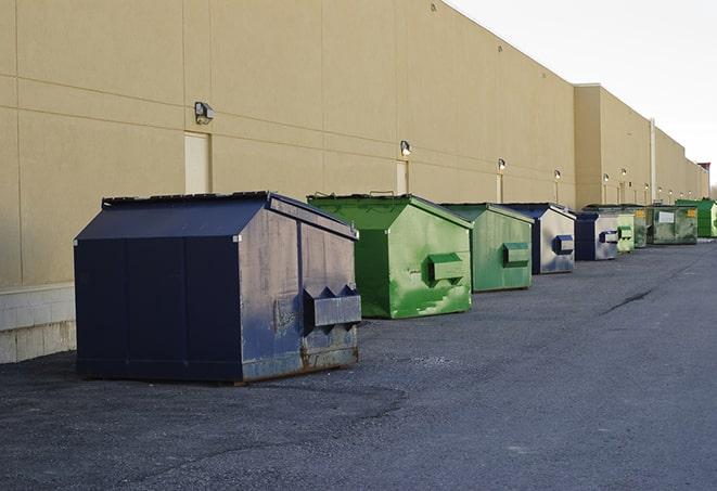 tilted front-load dumpsters being emptied by waste management workers in Charlestown